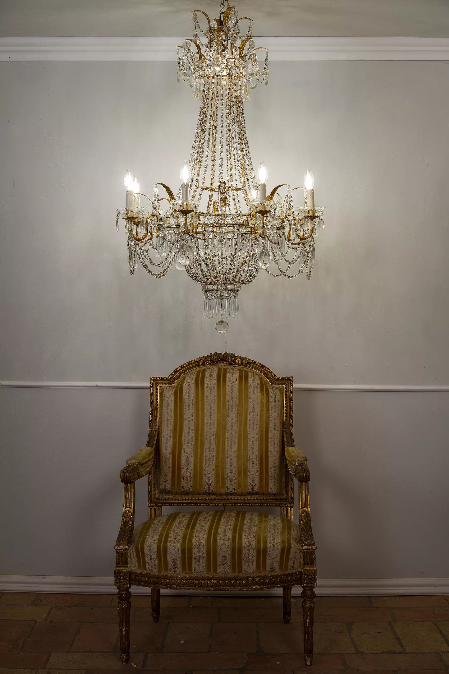 Antico lampadario del primo '900, riccamente decorato con cristalli e metallo dorato, espressione perfetta del lusso Belle Époque.| Lo Stile Italiano