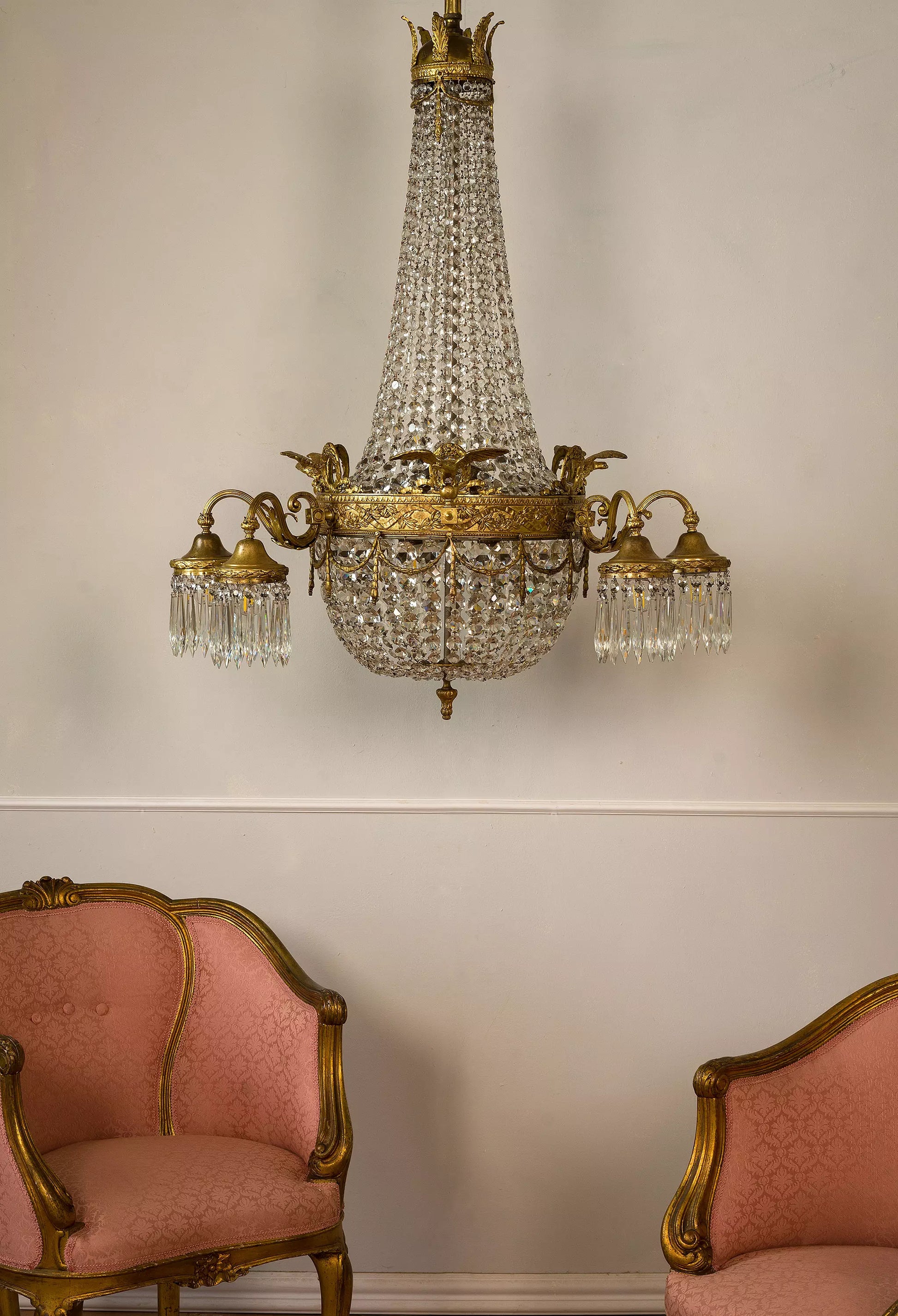 Lampadario in bronzo dorato decorato con accenti di cristallo, che evoca la grandiosità dello stile Impero.
Un capolavoro di raffinata artigianalità e fascino storico. | Lo-Stile-Italiano